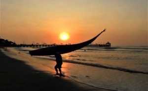 Man hauling Totora reed raft at sunset in Peru